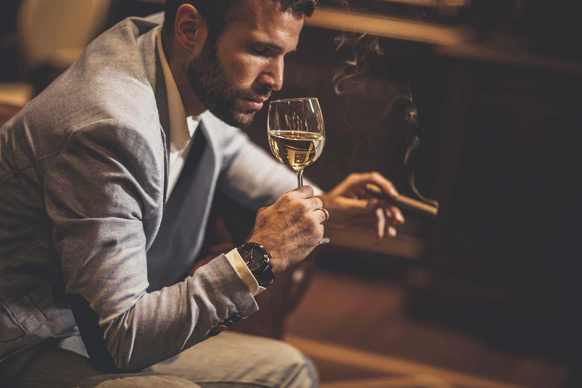 Man in strip club drinking wine and smoking cigar